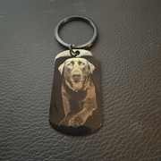 Black metal dog-tag keychain engraved with a dog portrait